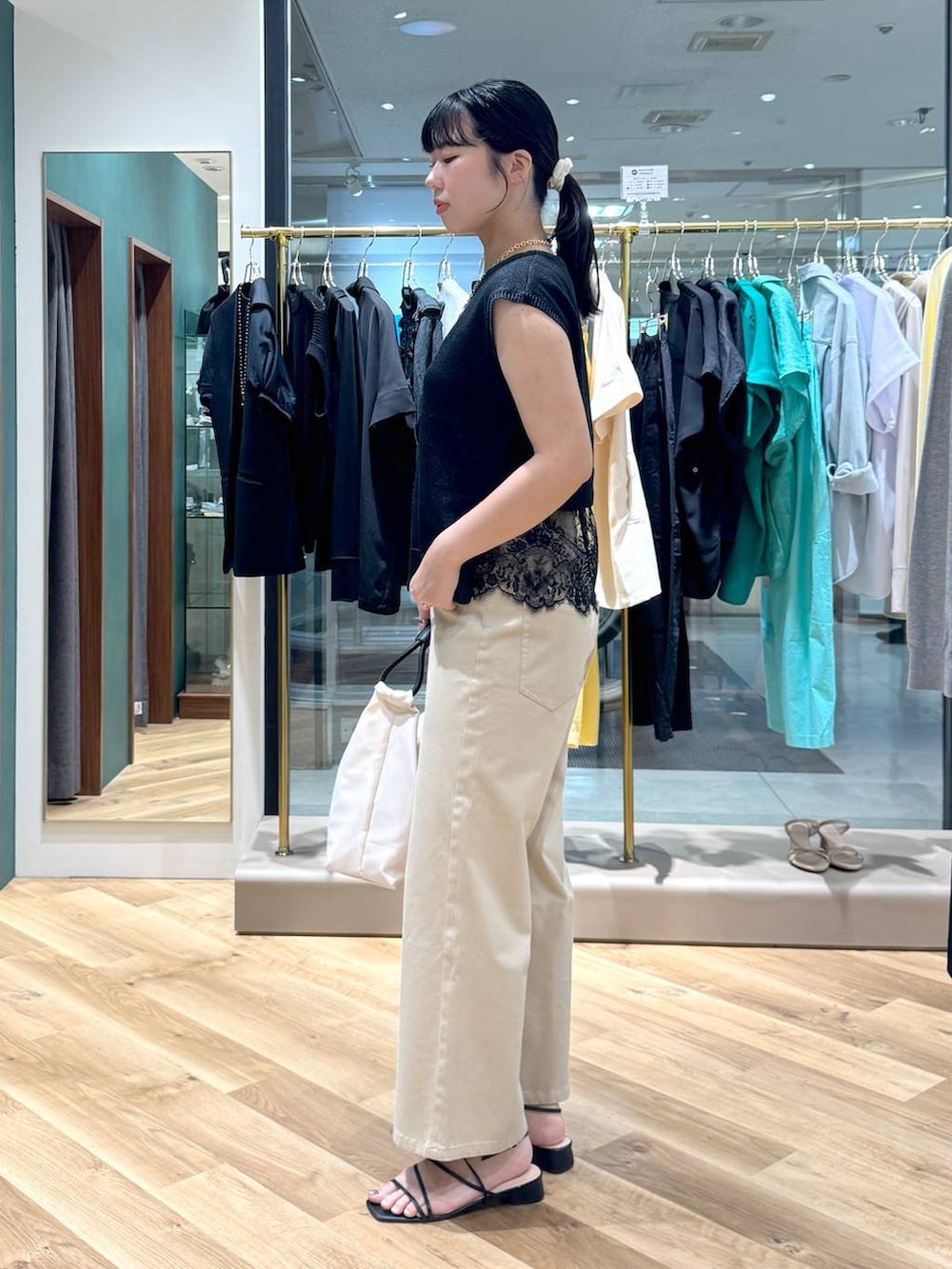 ベージュ系のデニムパンツ、ブラック系のニット/セーター、ホワイト系のトートバッグを着用したレディースの夏コーディネートの2枚目の写真