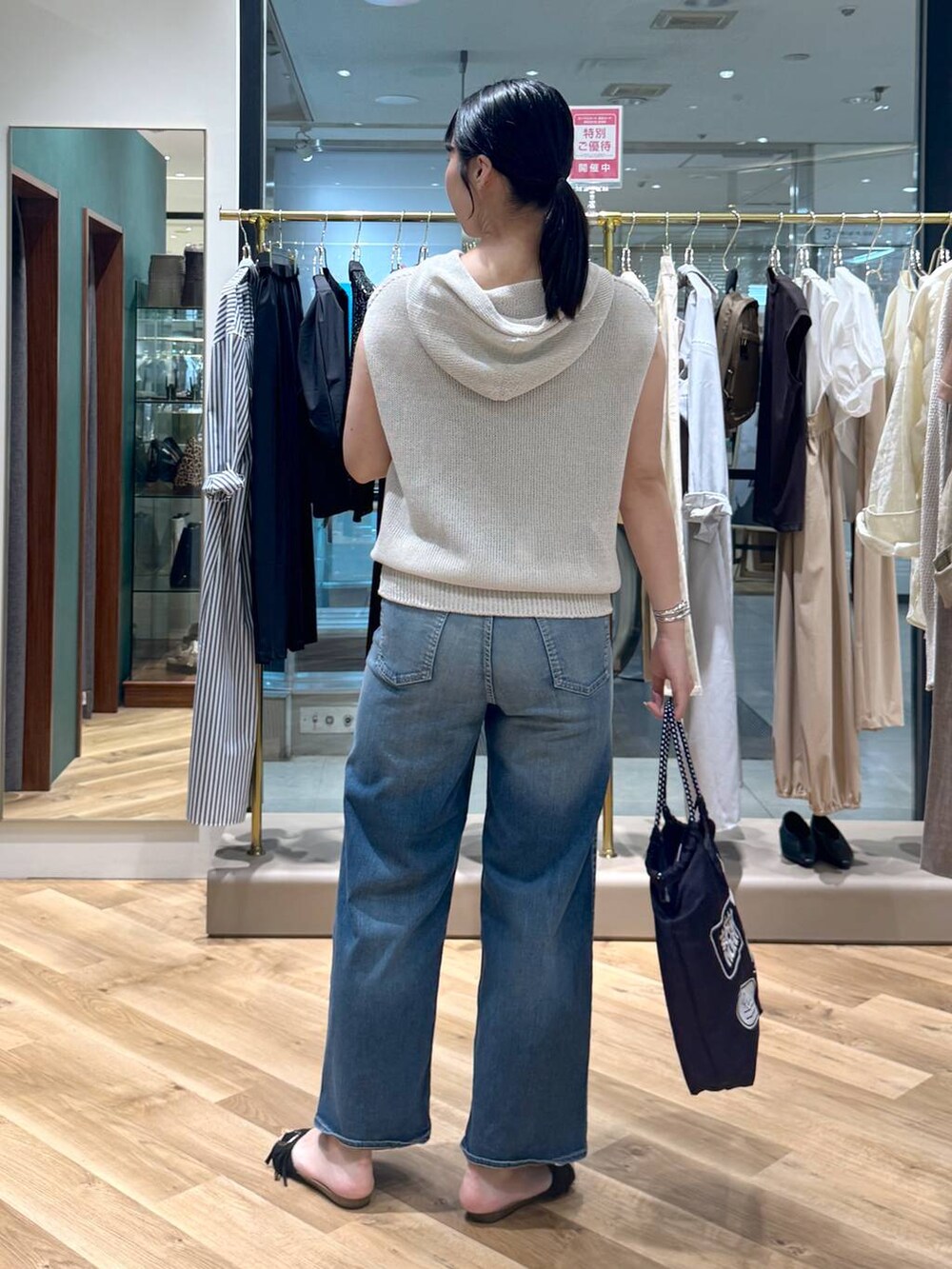 ブルー系のデニムパンツ、ベージュ系のニット/セーター、ブルー系のトートバッグを着用したレディースの春コーディネートの3枚目の写真
