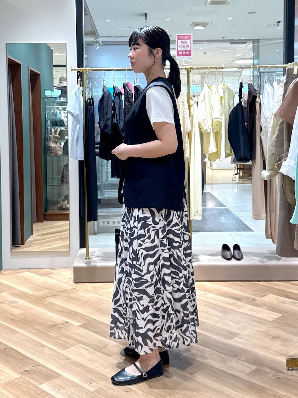 ブラック系のスカート、ブラック系のその他アウター、ホワイト系のTシャツ/カットソーを着用したレディースの春コーディネートの2枚目の写真