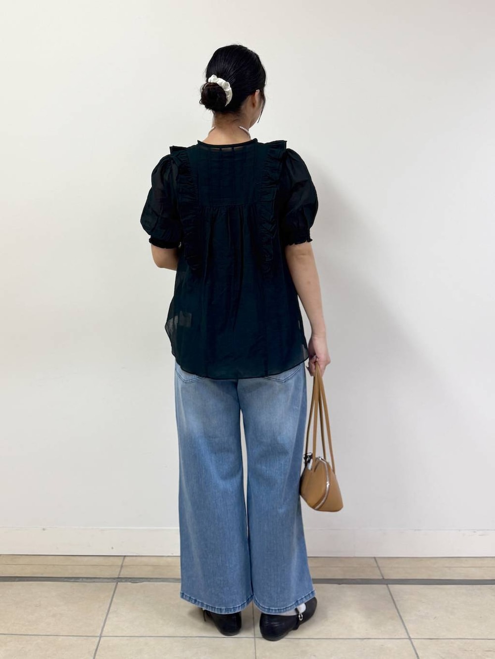 ブルー系のデニムパンツ、ブラック系のシャツ/ブラウス、ブラウン系のハンドバッグを着用したレディースの春コーディネートの3枚目の写真