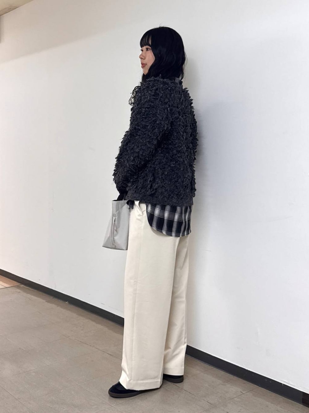 ホワイト系のトートバッグ、ホワイト系のスラックス、グレー系のカーディガン/ボレロを着用したレディースの冬コーディネートの2枚目の写真