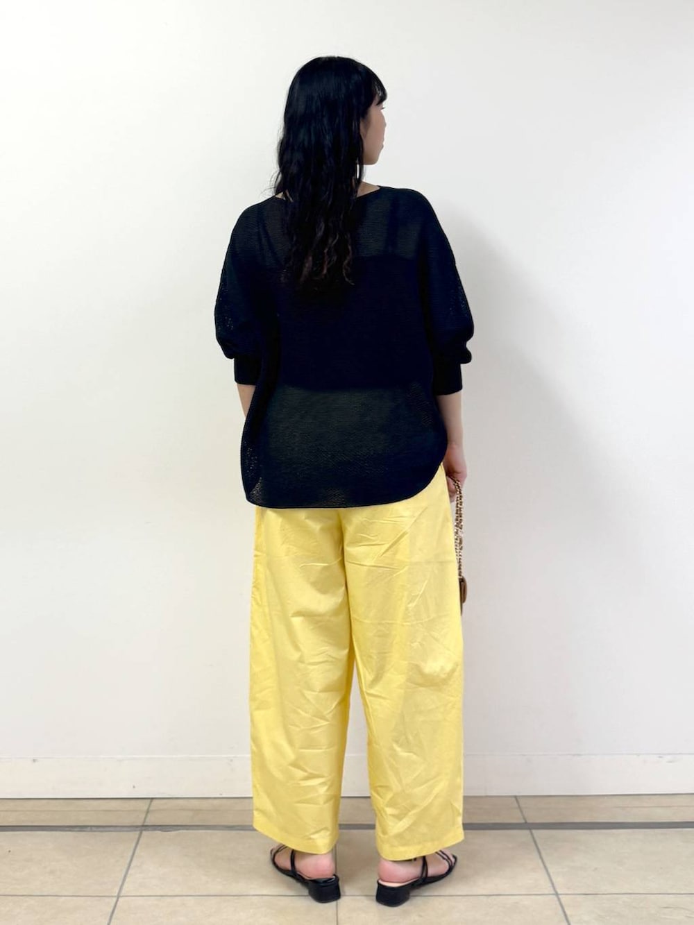 イエロー系のその他パンツ、ブラック系のキャミソール、ブラック系のニット/セーターを着用したレディースの春コーディネートの3枚目の写真