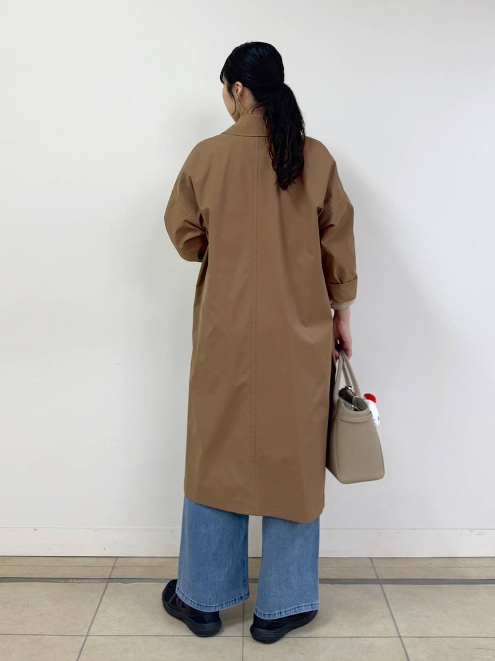 ブルー系のデニムパンツ、ベージュ系のシャツ/ブラウス、イエロー系のステンカラーコートを着用したレディースの冬コーディネートの3枚目の写真