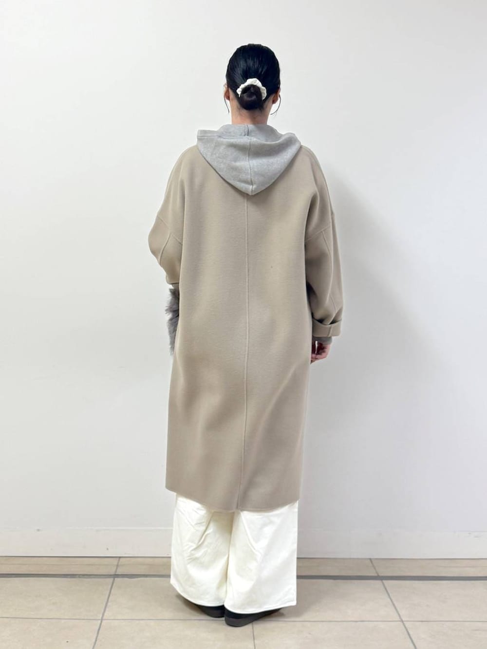 ベージュ系のニット/セーター、ブラウン系のトートバッグ、ベージュ系のチェスターコートを着用したレディースの秋コーディネートの3枚目の写真