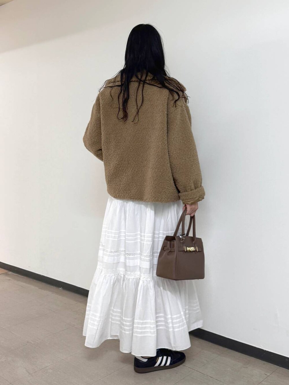 イエロー系のピーコート、ベージュ系のショルダーバッグ、ホワイト系のスカートを着用したレディースの秋コーディネートの3枚目の写真