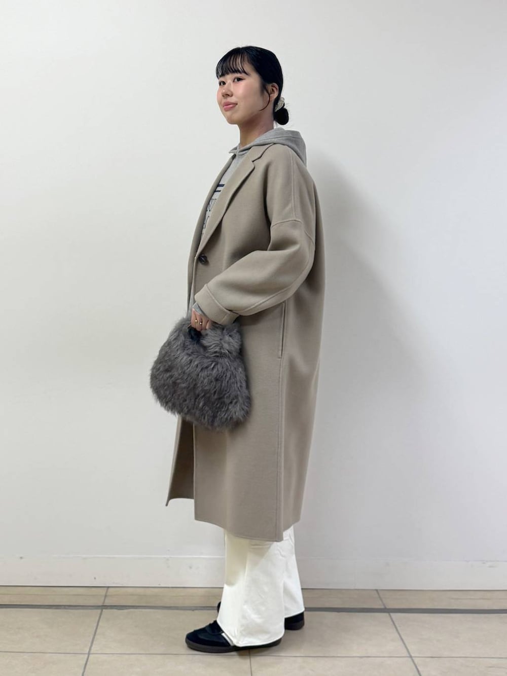 ベージュ系のニット/セーター、ブラウン系のトートバッグ、ベージュ系のチェスターコートを着用したレディースの秋コーディネートの2枚目の写真