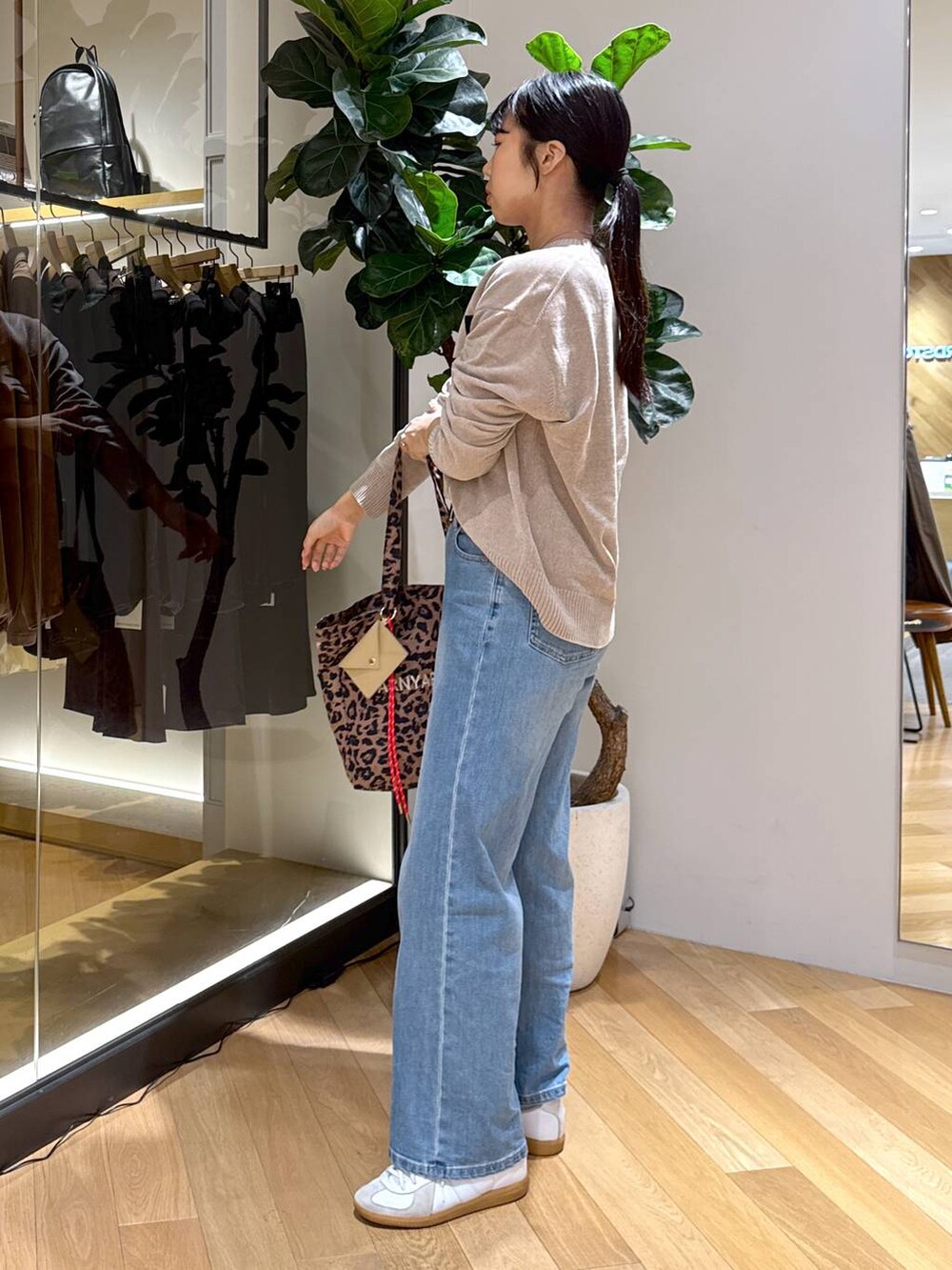 ブルー系のデニムパンツ、その他のトートバッグ、ベージュ系のニット/セーターを着用したレディースの秋コーディネートの2枚目の写真