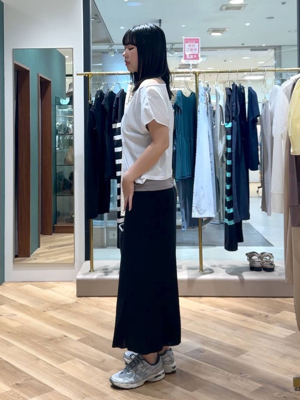 ブラック系のトートバッグ、ブラック系のスカート、ホワイト系のTシャツ/カットソーを着用したレディースの春コーディネートの2枚目の写真