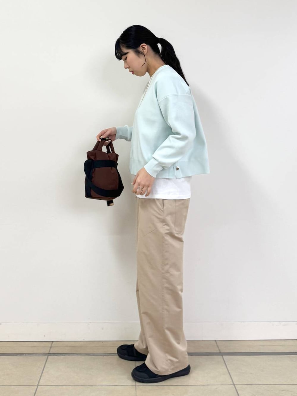 ブラウン系のショルダーバッグ、ブルー系のニット/セーター、ベージュ系のその他パンツを着用したレディースの冬コーディネートの2枚目の写真