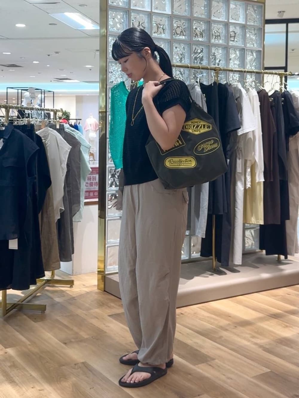 ブラック系のニット/セーター、ベージュ系のその他パンツ、グリーン系のトートバッグを着用したレディースの夏コーディネートの2枚目の写真