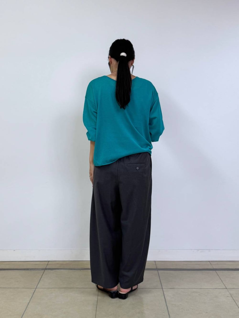 ブラック系のハンドバッグ、グリーン系のニット/セーター、グレー系のその他パンツを着用したレディースの夏コーディネートの3枚目の写真