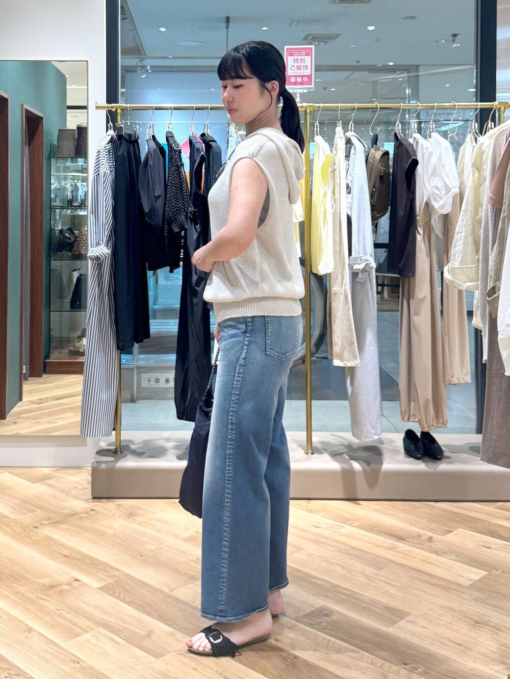 ブルー系のデニムパンツ、ベージュ系のニット/セーター、ブルー系のトートバッグを着用したレディースの春コーディネートの2枚目の写真