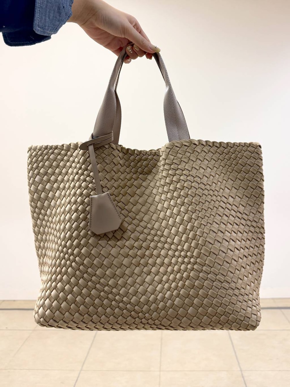 ブルー系のニット/セーター、ベージュ系のトートバッグ、ホワイト系のカーゴパンツを着用したレディースの冬コーディネートの5枚目の写真