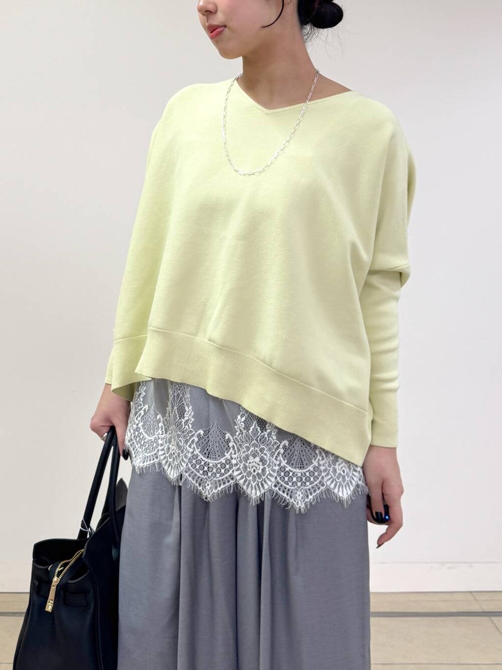 イエロー系のニット/セーター、ブラック系のトートバッグ、グレー系のその他パンツを着用したレディースの冬コーディネートの4枚目の写真