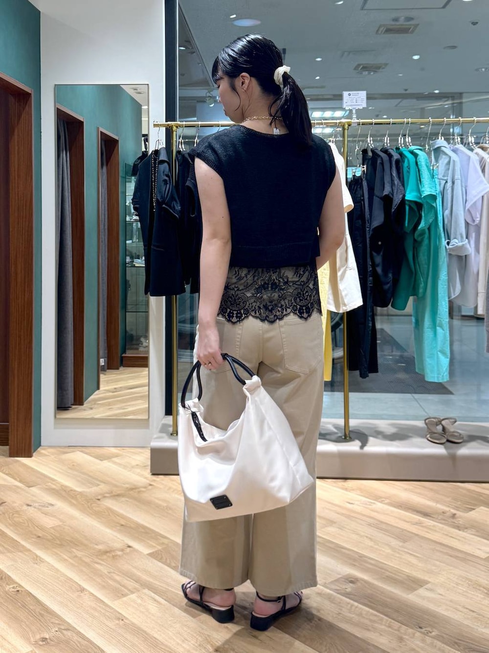 ベージュ系のデニムパンツ、ブラック系のニット/セーター、ホワイト系のトートバッグを着用したレディースの夏コーディネートの3枚目の写真