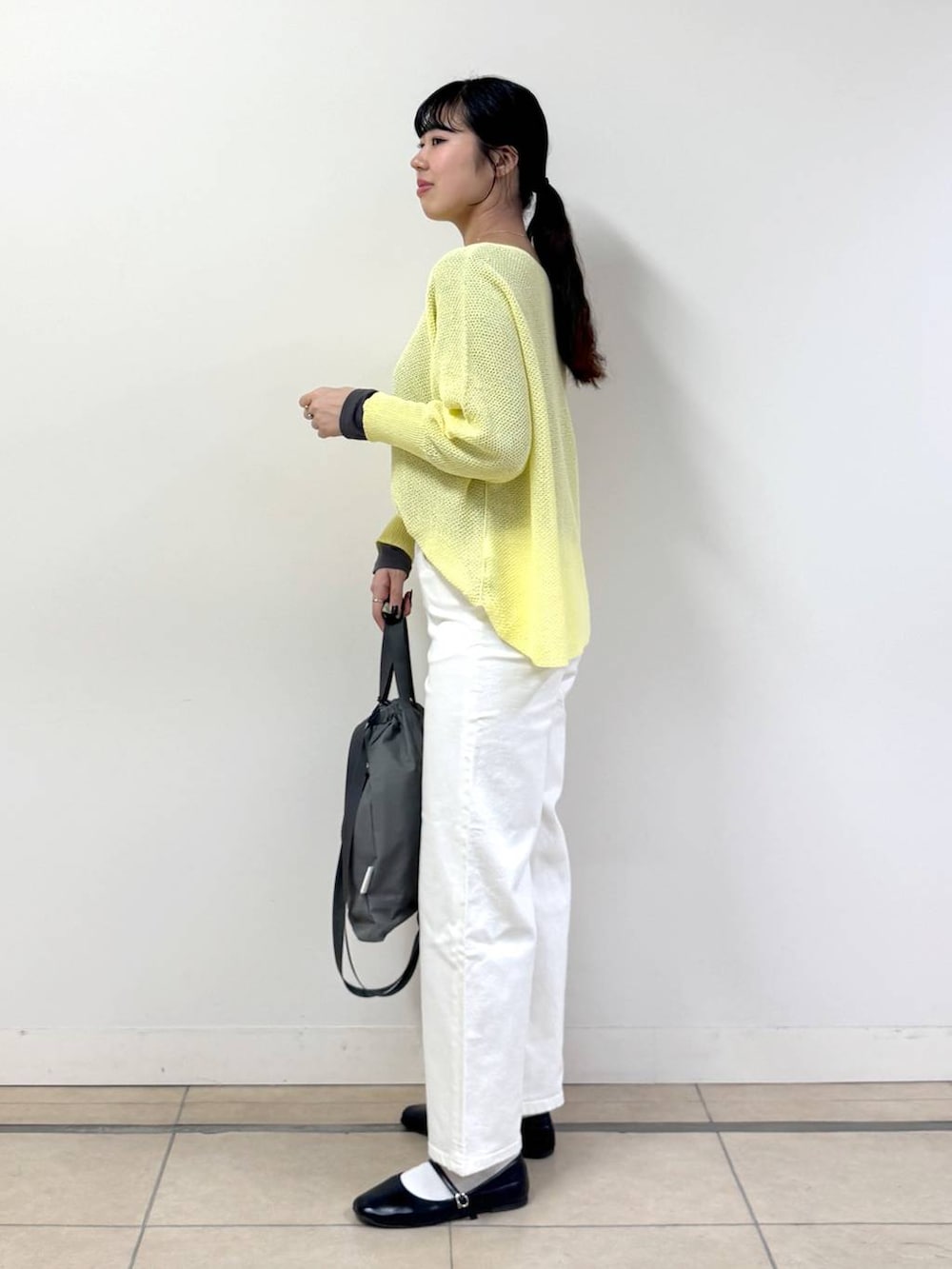 ホワイト系のデニムパンツ、グレー系のTシャツ/カットソー、イエロー系のニット/セーターを着用したレディースの春コーディネートの2枚目の写真