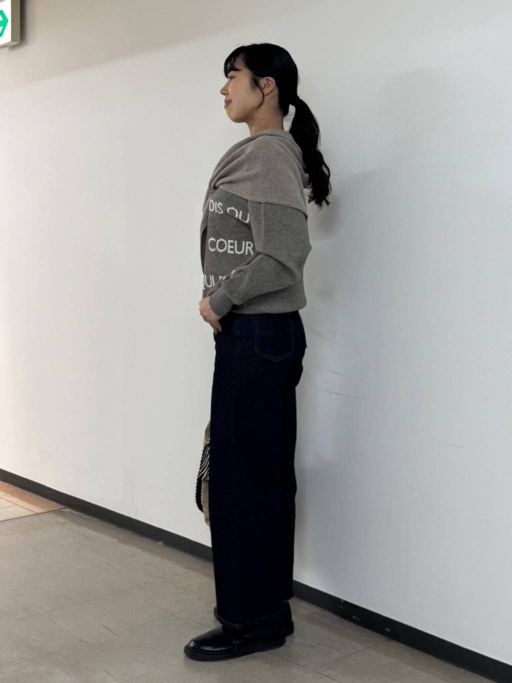 ブルー系のデニムパンツ、ブラウン系のバックパック/リュック、グレー系のニット/セーターを着用したレディースの秋コーディネートの2枚目の写真