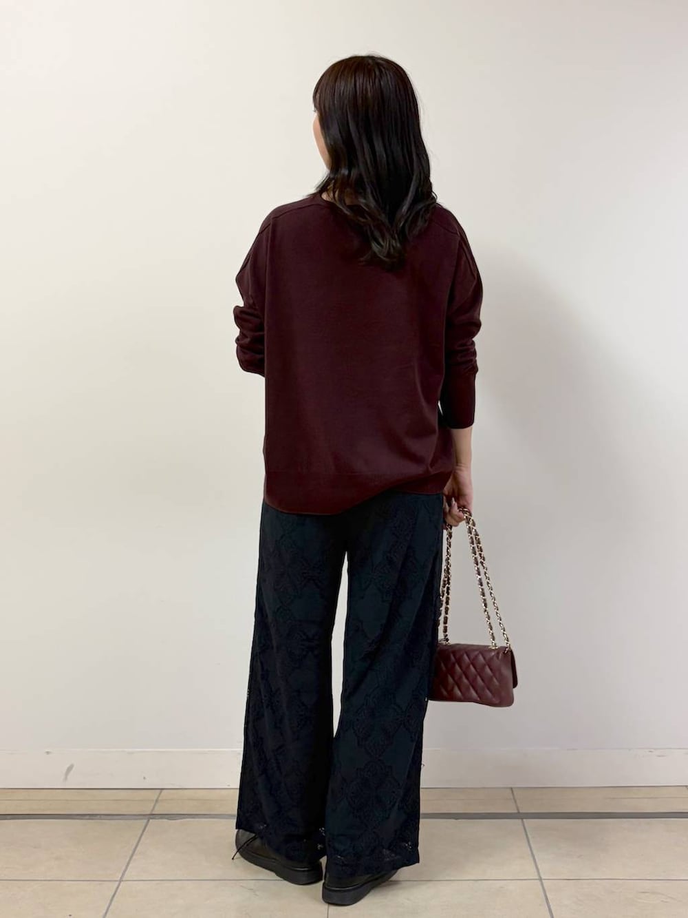 ブラウン系のハンドバッグ、ブラック系のその他パンツ、レッド系のニット/セーターを着用したレディースの秋コーディネートの3枚目の写真