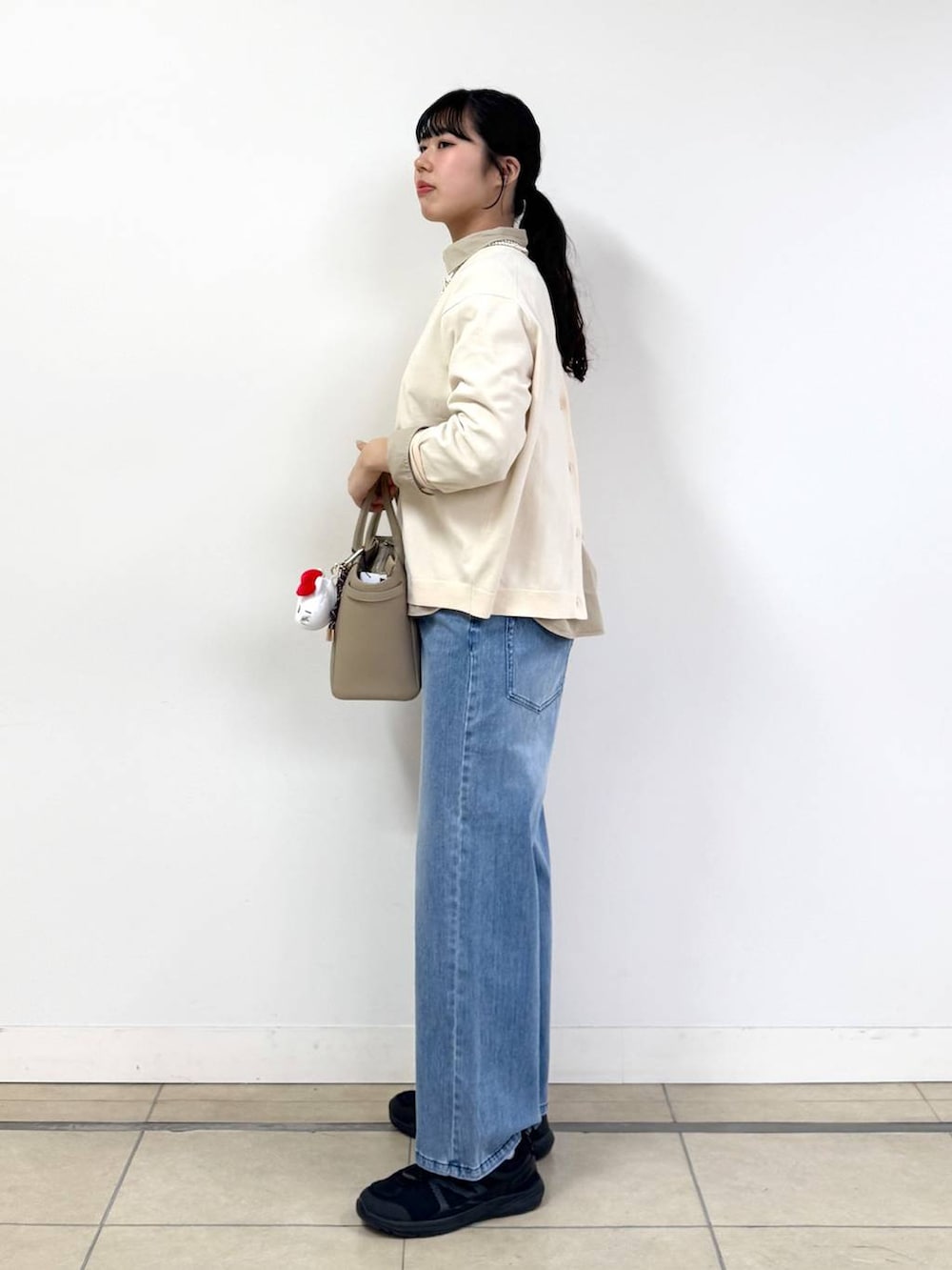 ブルー系のデニムパンツ、ベージュ系のシャツ/ブラウス、ホワイト系のニット/セーターを着用したレディースの冬コーディネートの2枚目の写真