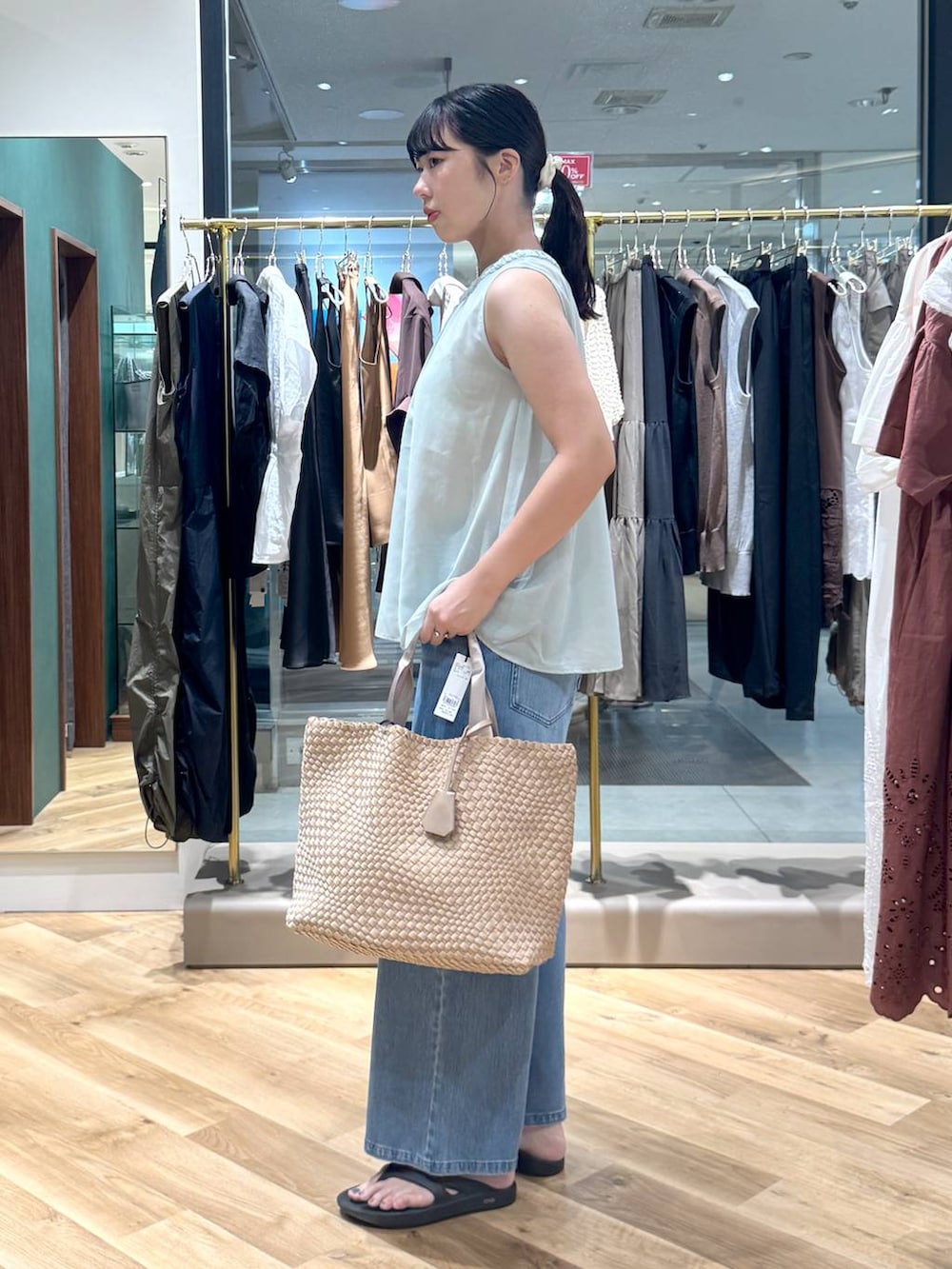 ブルー系のデニムパンツ、ベージュ系のトートバッグ、グリーン系のシャツ/ブラウスを着用したレディースの夏コーディネートの2枚目の写真