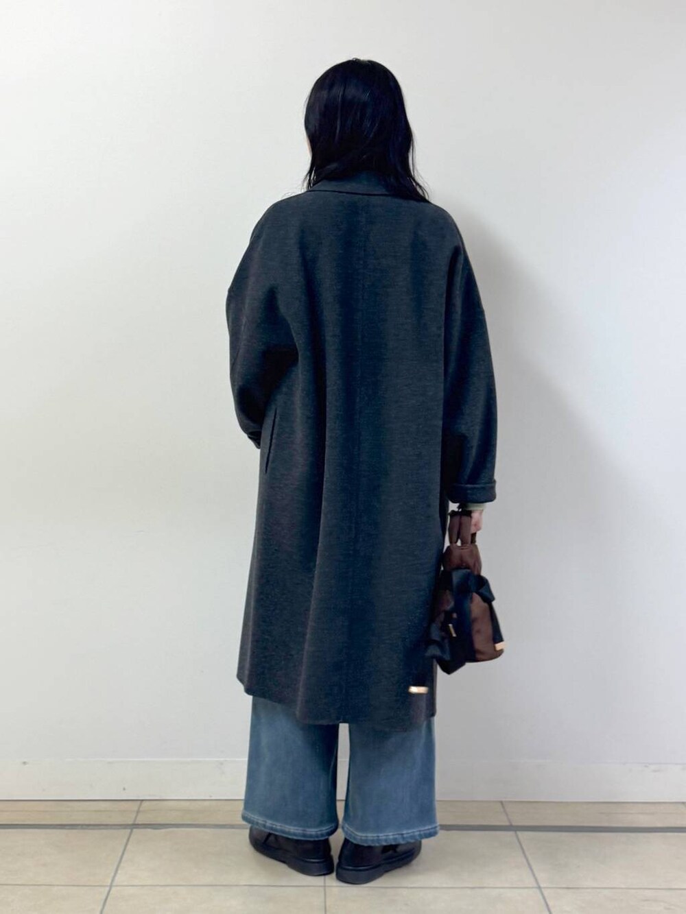 グリーン系のニット/セーター、ブルー系のデニムパンツ、グレー系のチェスターコートを着用したレディースの秋コーディネートの3枚目の写真