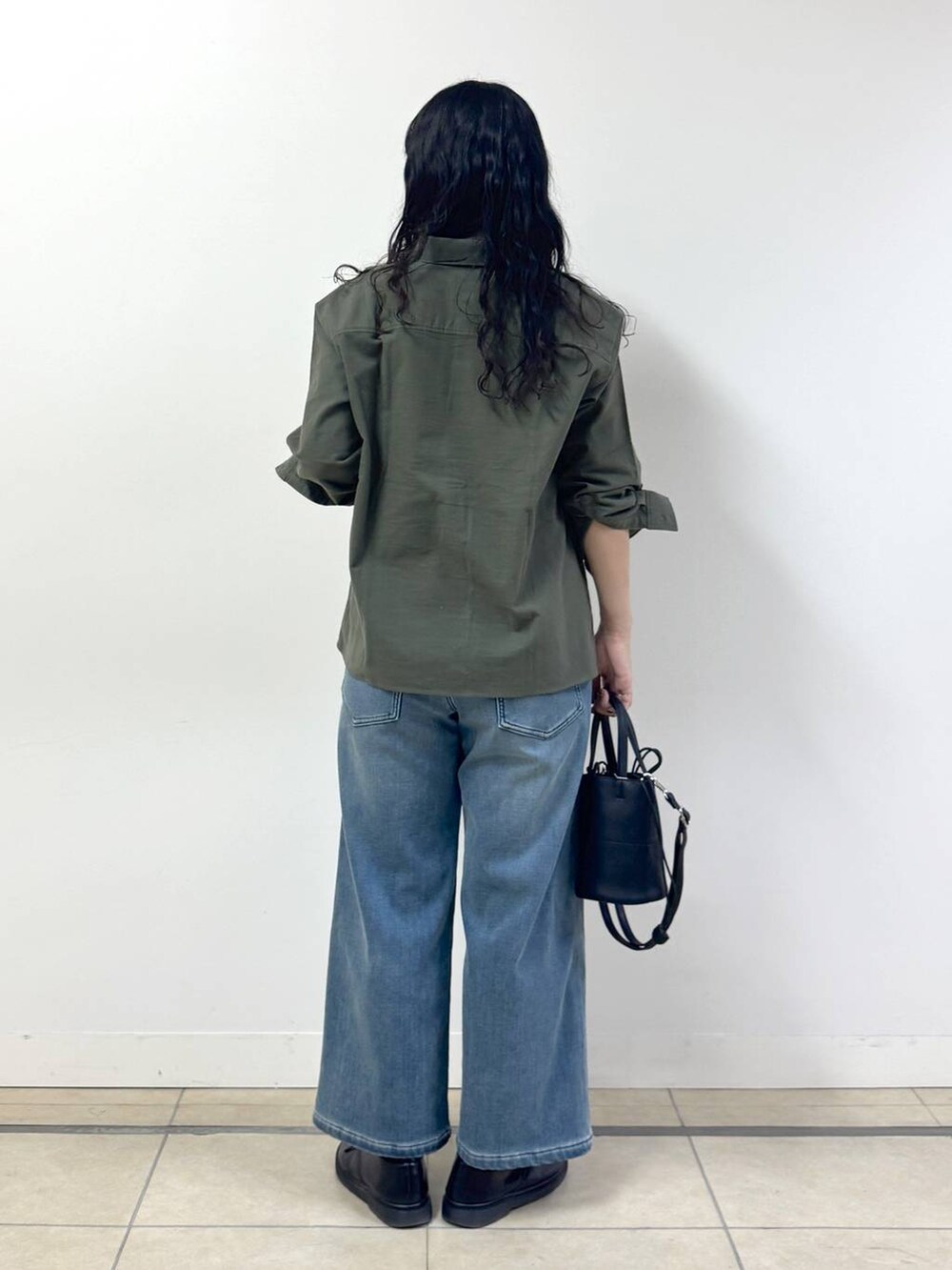 ブルー系のデニムパンツ、ブラック系のブルゾン、グリーン系のシャツ/ブラウスを着用したレディースの冬コーディネートの3枚目の写真