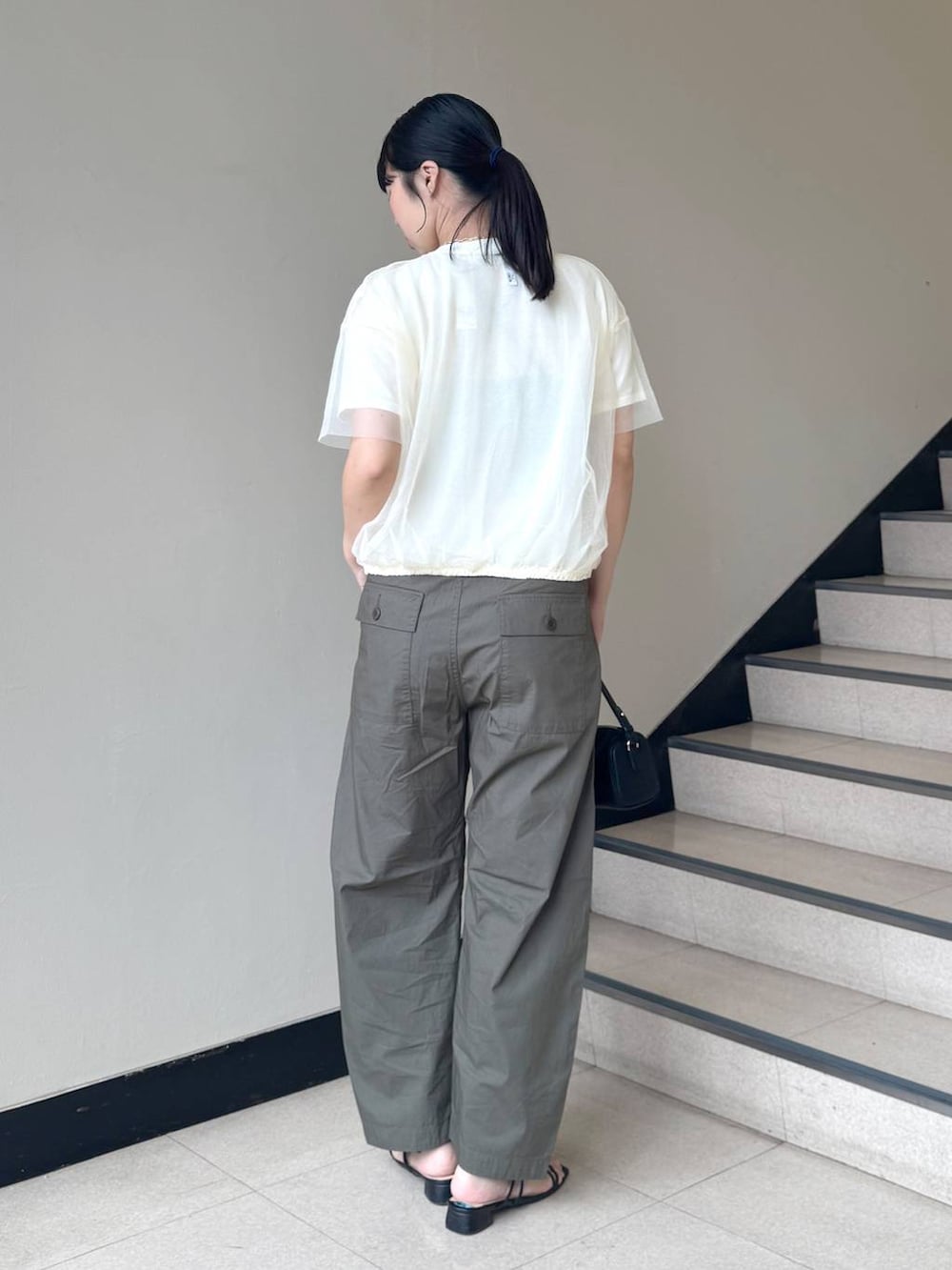 ブラック系のハンドバッグ、グリーン系のカーゴパンツ、ホワイト系のニット/セーターを着用したレディースの夏コーディネートの3枚目の写真