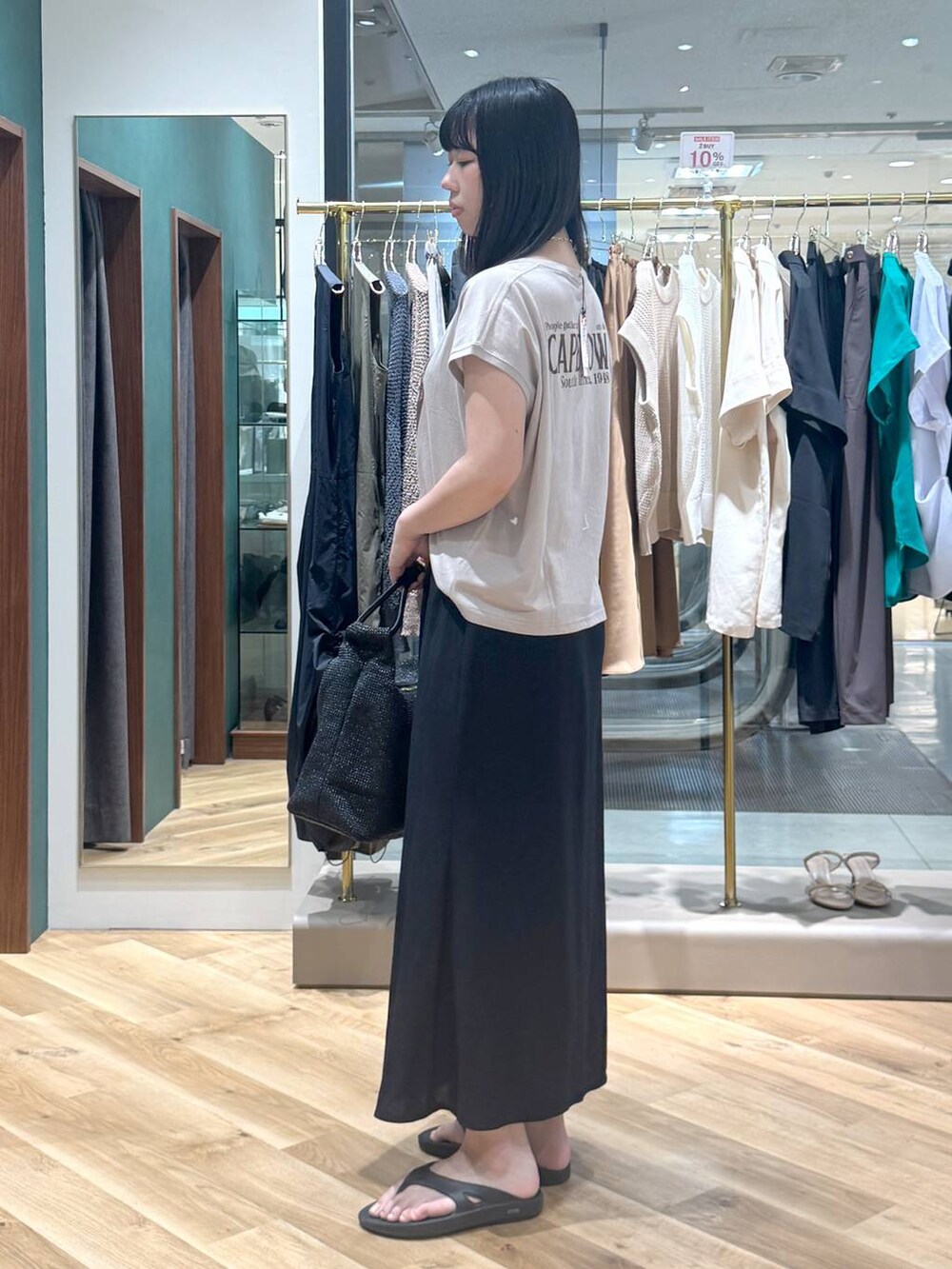 ベージュ系のTシャツ/カットソー、ブラック系のスカート、ブラック系のトートバッグを着用したレディースの夏コーディネートの2枚目の写真