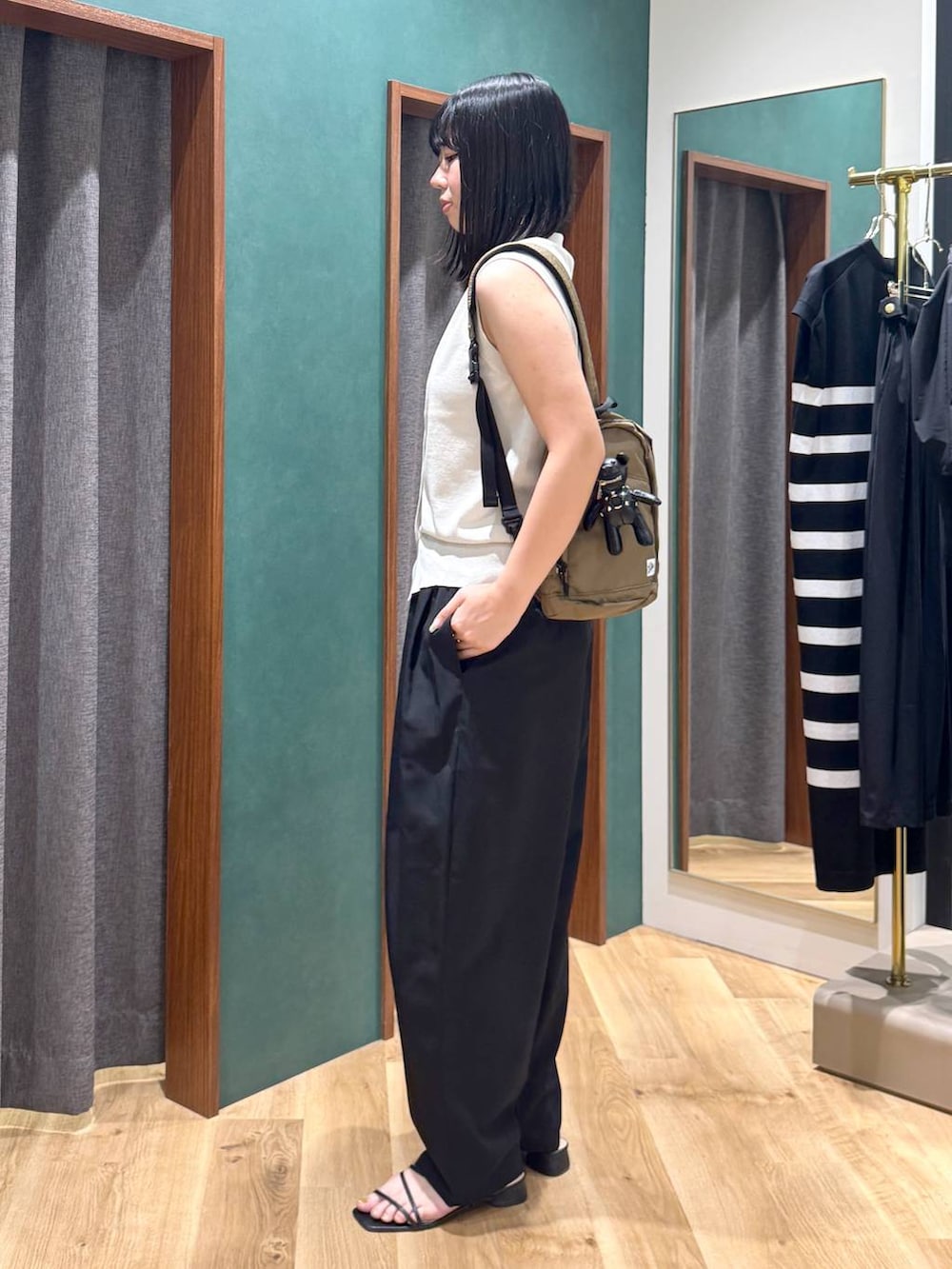 ブラック系のその他パンツ、グリーン系のバックパック/リュック、ベージュ系のベストを着用したレディースの春コーディネートの2枚目の写真