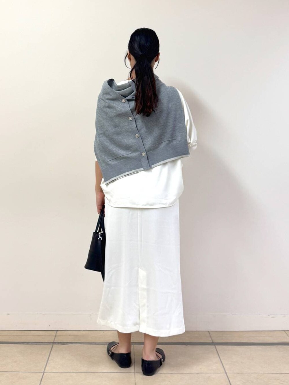 ホワイト系のスカート、ホワイト系のTシャツ/カットソー、グレー系のカーディガン/ボレロを着用したレディースの冬コーディネートの3枚目の写真