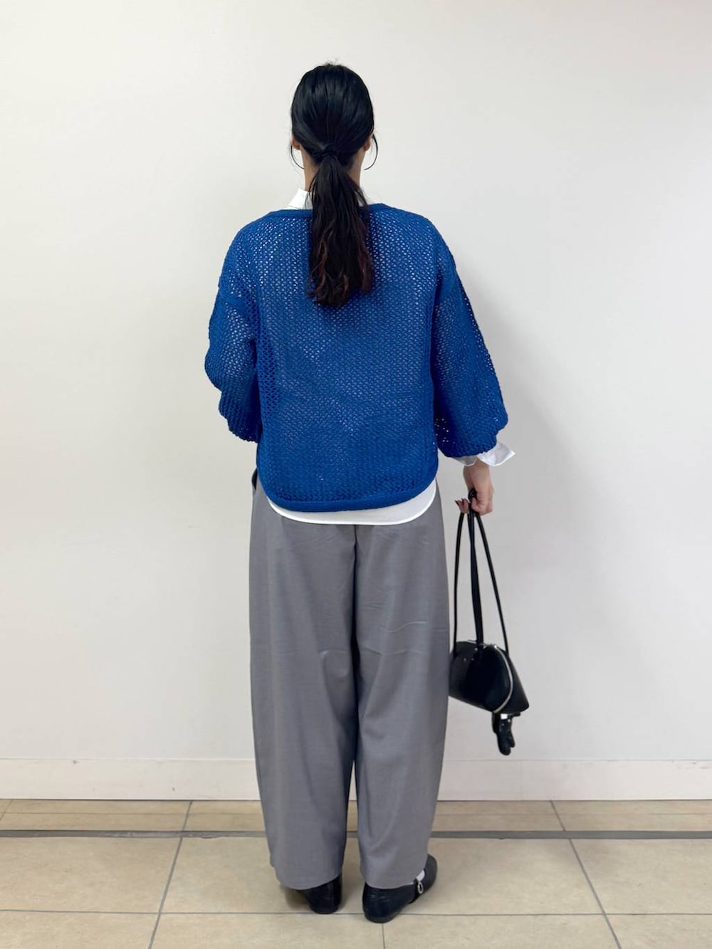 ブルー系のニット/セーター、ホワイト系のシャツ/ブラウス、ブラック系のハンドバッグを着用したレディースの冬コーディネートの3枚目の写真