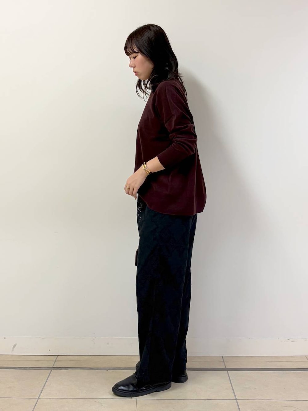 ブラウン系のハンドバッグ、ブラック系のその他パンツ、レッド系のニット/セーターを着用したレディースの秋コーディネートの2枚目の写真