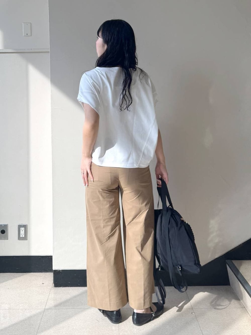 ベージュ系のその他パンツ、ホワイト系のTシャツ/カットソー、ブラック系のバックパック/リュックを着用したレディースの春コーディネートの3枚目の写真