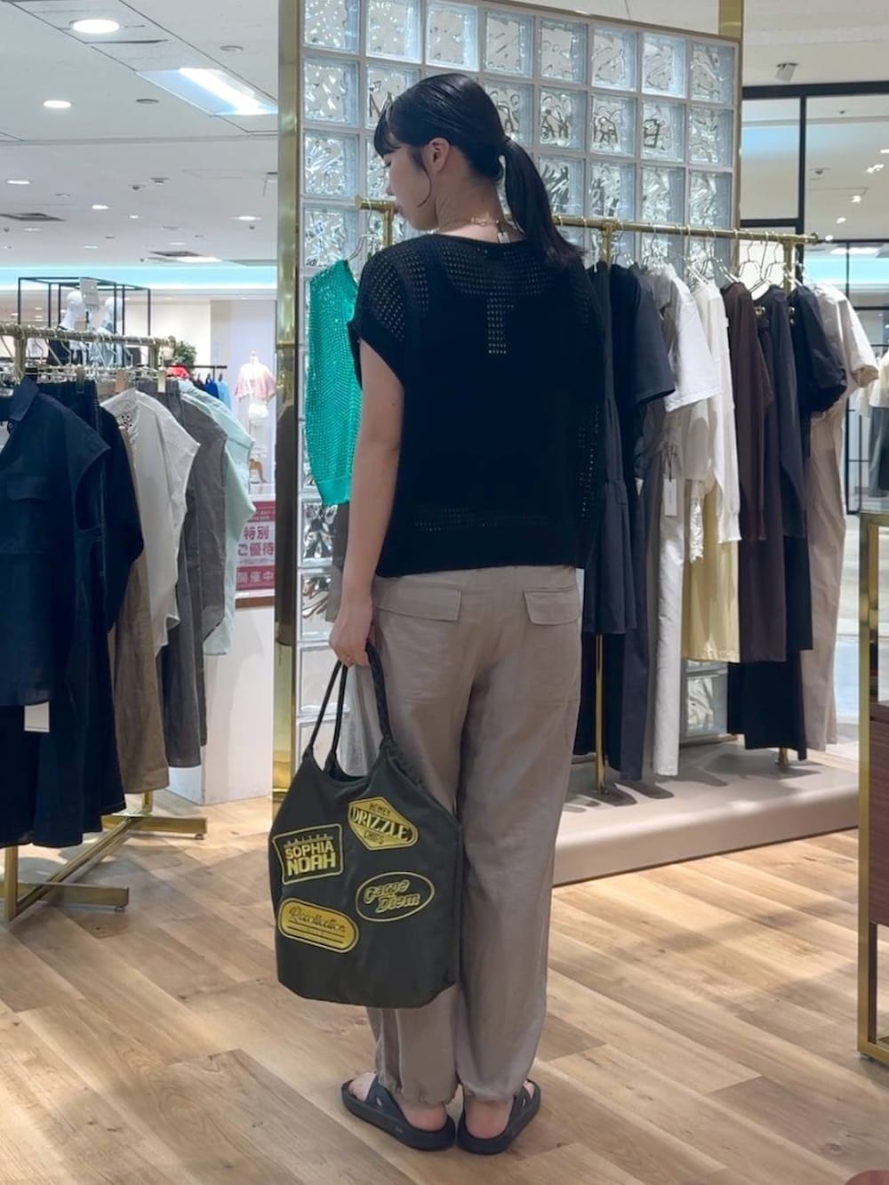ブラック系のニット/セーター、ベージュ系のその他パンツ、グリーン系のトートバッグを着用したレディースの夏コーディネートの3枚目の写真