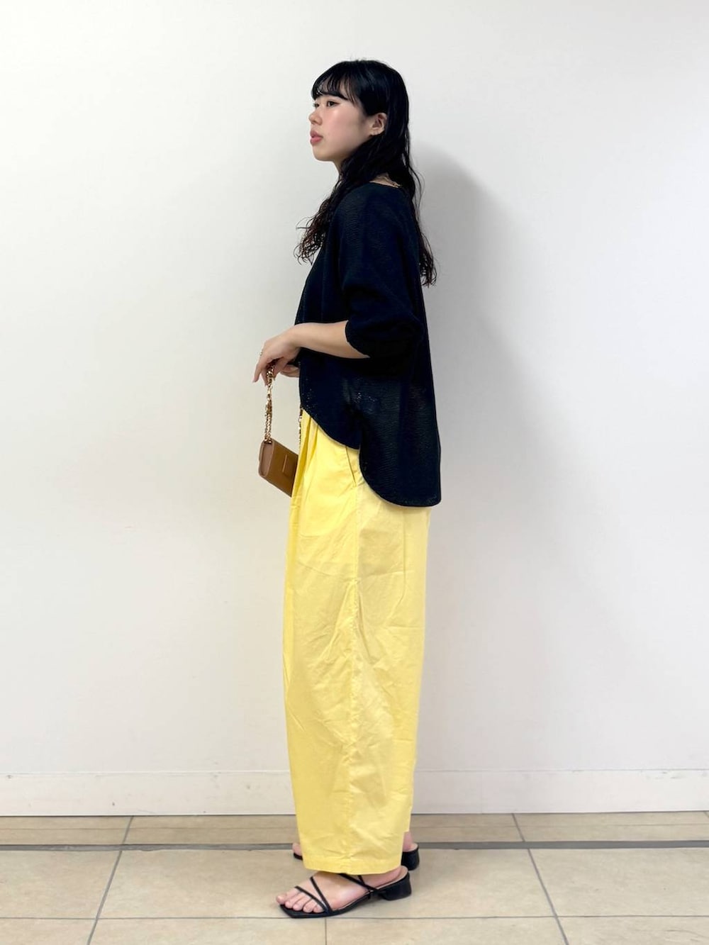 イエロー系のその他パンツ、ブラック系のキャミソール、ブラック系のニット/セーターを着用したレディースの春コーディネートの2枚目の写真