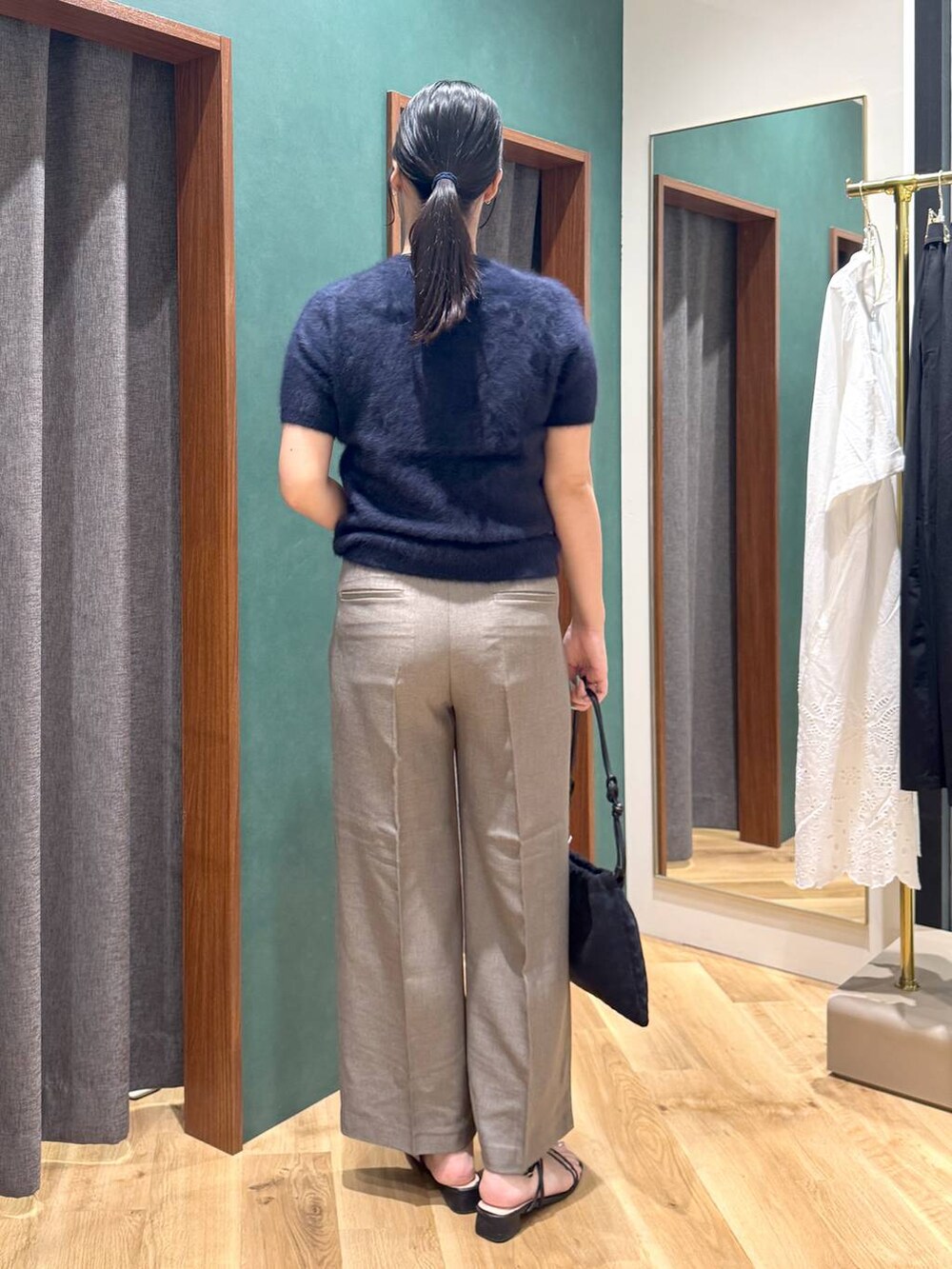 ブラック系のショルダーバッグ、ブルー系のニット/セーター、ベージュ系のスラックスを着用したレディースの夏コーディネートの3枚目の写真