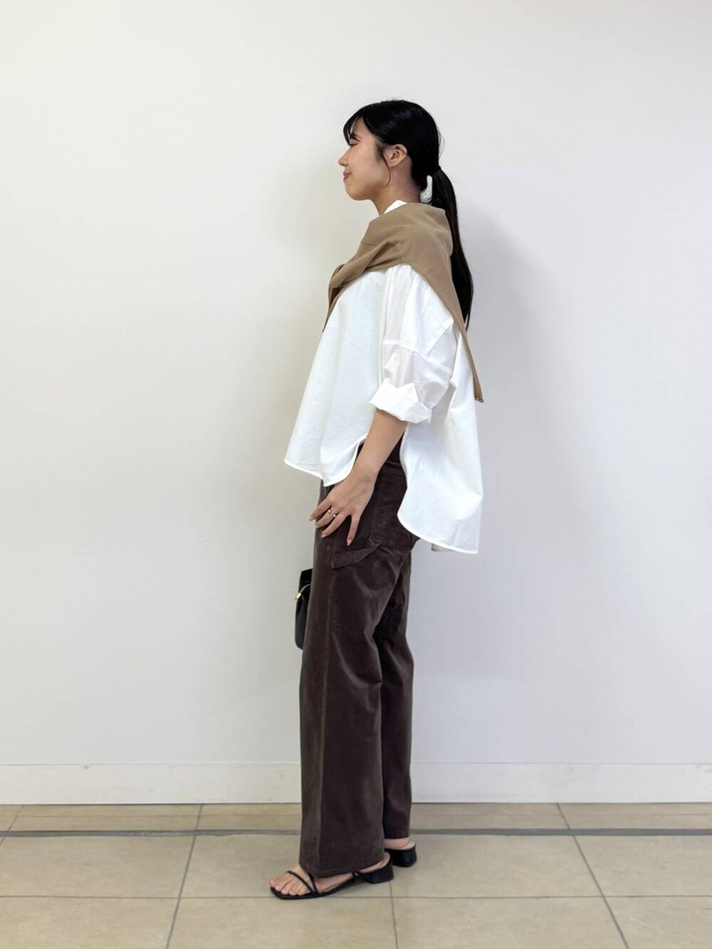 ブラック系のショルダーバッグ、ホワイト系のシャツ/ブラウス、ベージュ系のニット/セーターを着用したレディースの夏コーディネートの2枚目の写真