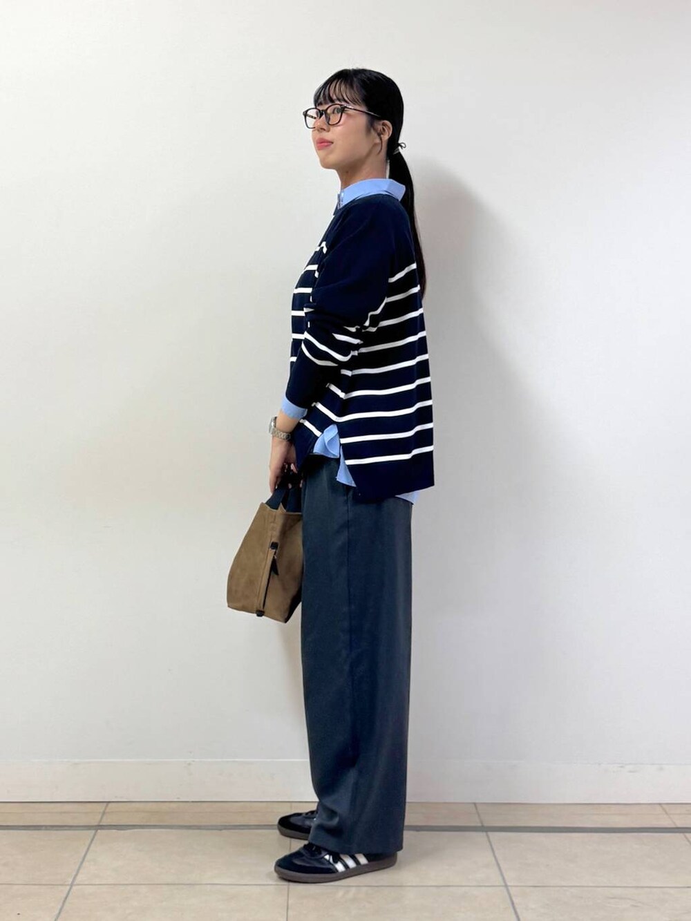 ブルー系のシャツ/ブラウス、グレー系のスラックス、イエロー系のトートバッグを着用したレディースの秋コーディネートの2枚目の写真