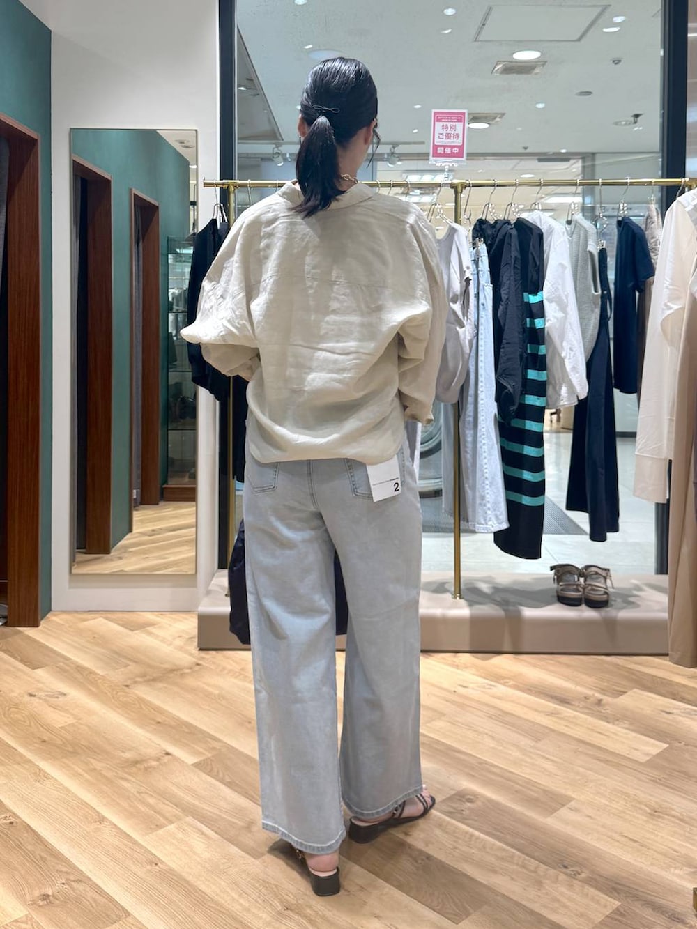 ブルー系のデニムパンツ、ブルー系のトートバッグ、ベージュ系のシャツ/ブラウスを着用したレディースの夏コーディネートの3枚目の写真