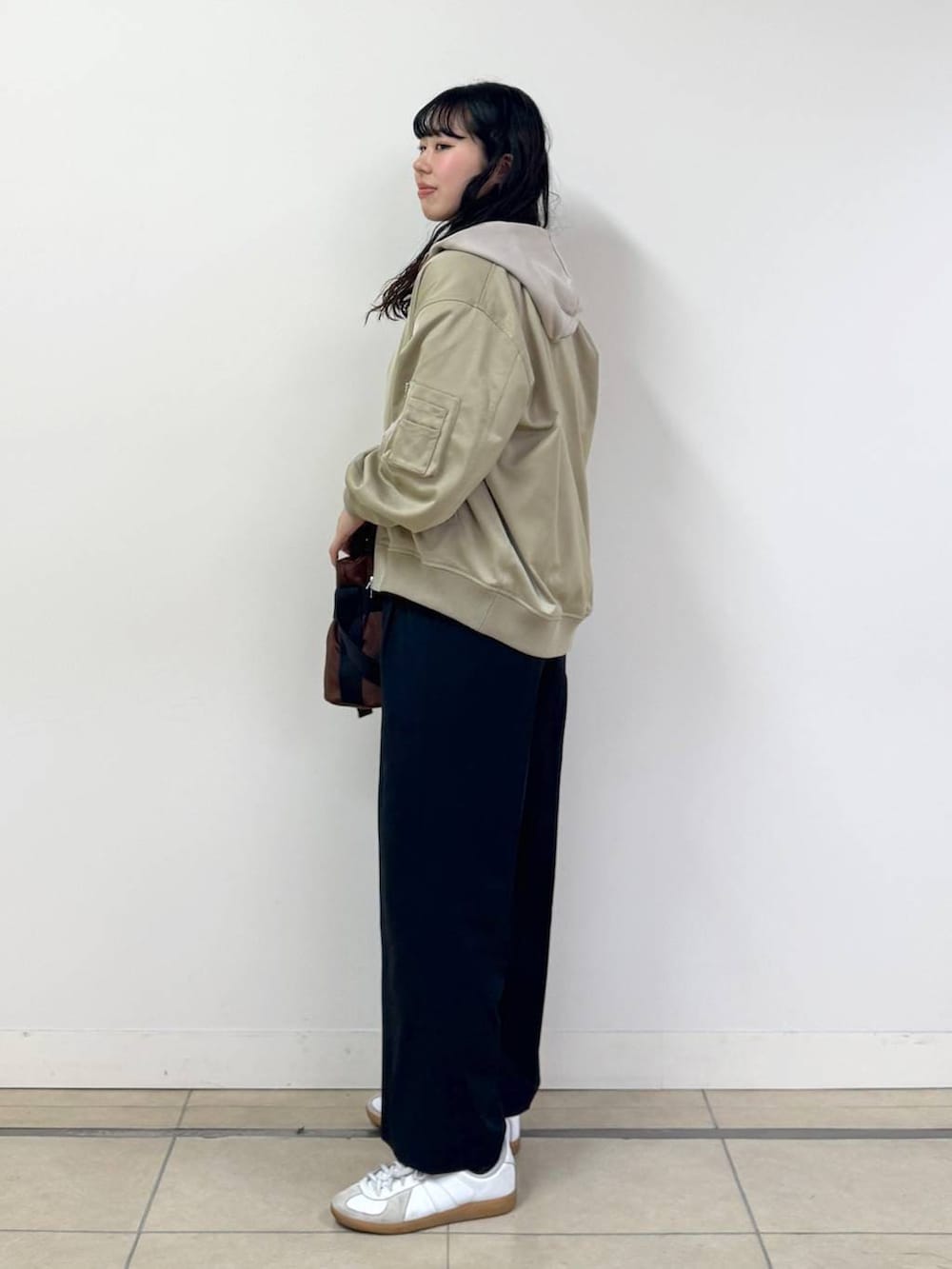 ブラウン系のショルダーバッグ、ベージュ系のパーカー、ブラック系のその他パンツを着用したレディースの冬コーディネートの2枚目の写真