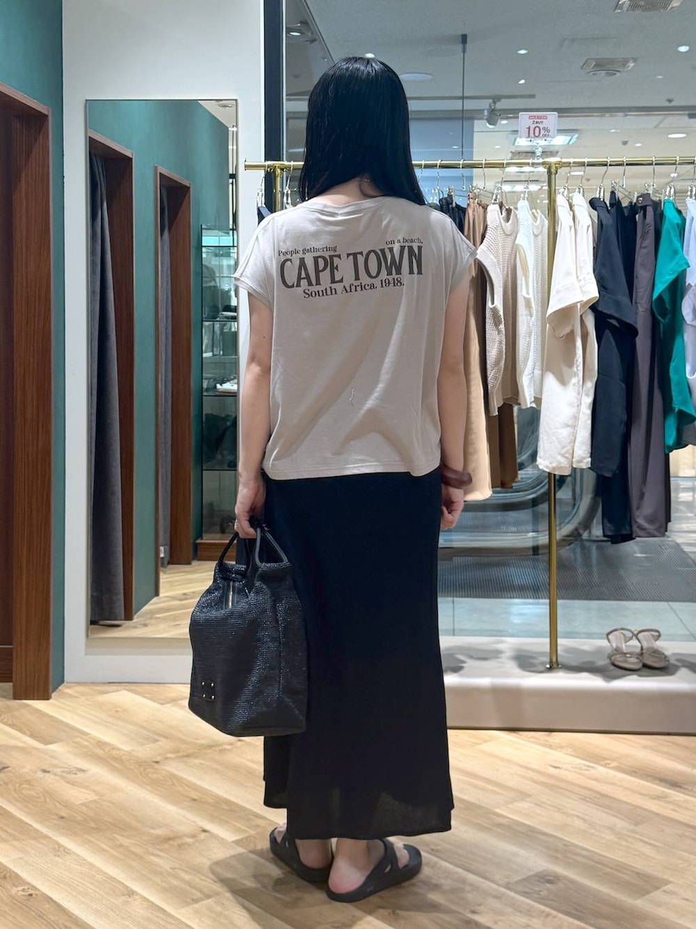 ベージュ系のTシャツ/カットソー、ブラック系のスカート、ブラック系のトートバッグを着用したレディースの夏コーディネートの3枚目の写真