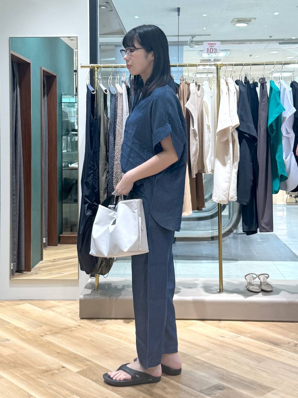 ホワイト系のトートバッグ、ブルー系のシャツ/ブラウス、ブルー系のデニムパンツを着用したレディースの夏コーディネートの2枚目の写真