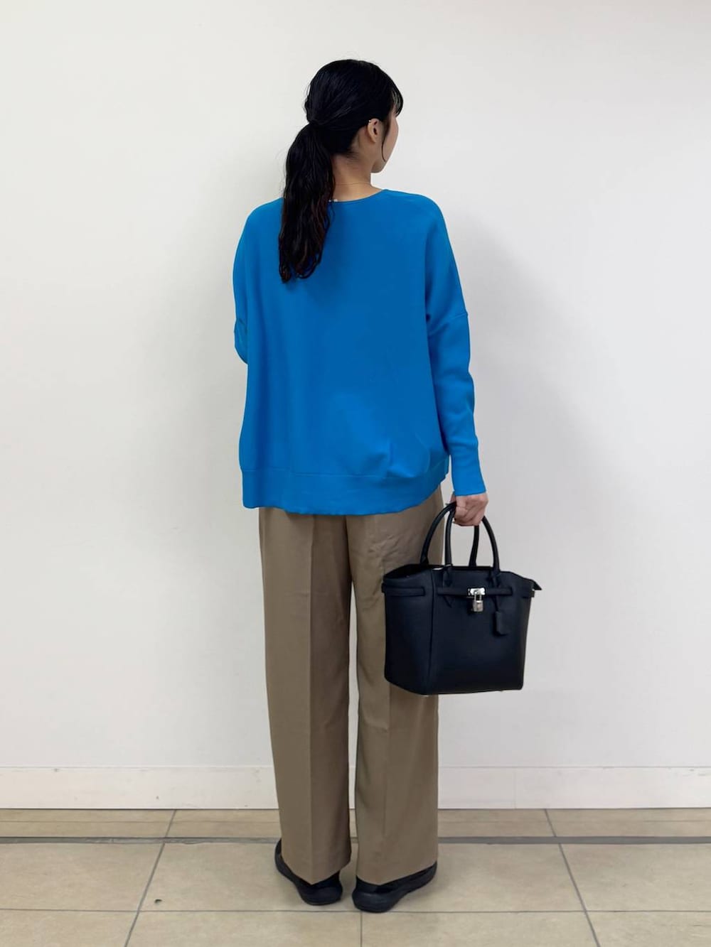 ブルー系のニット/セーター、ベージュ系のその他パンツ、ブラック系のハンドバッグを着用したレディースの冬コーディネートの3枚目の写真