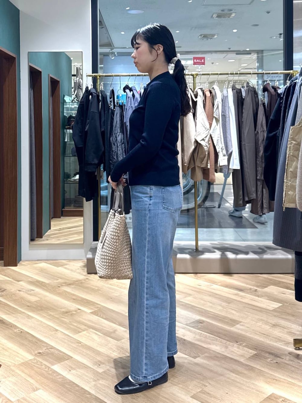 ブルー系のデニムパンツ、ブルー系のニット/セーター、ベージュ系のトートバッグを着用したレディースの冬コーディネートの2枚目の写真