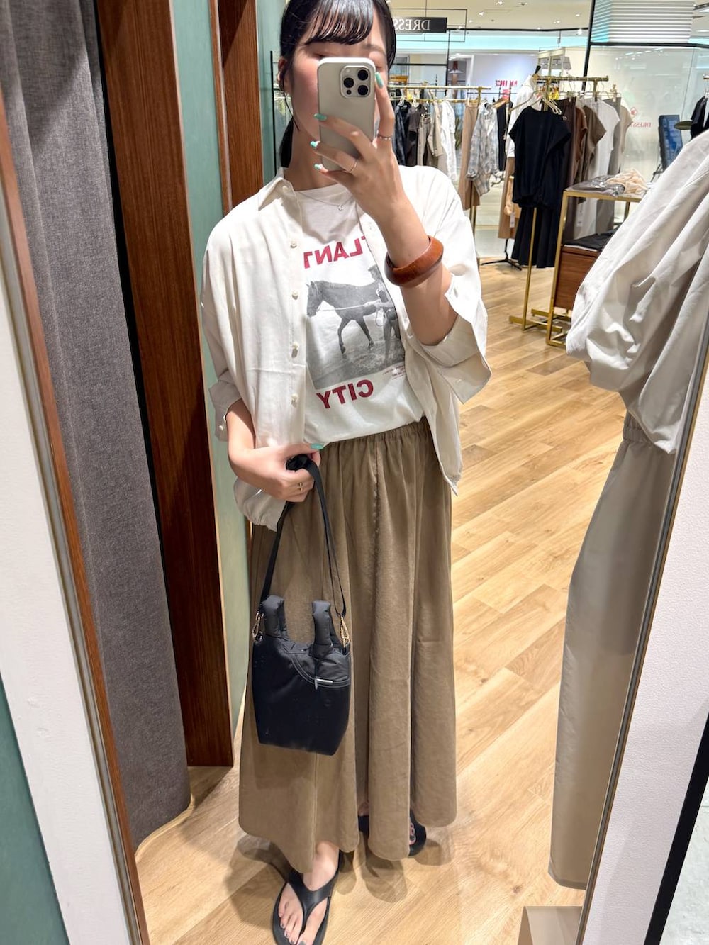 ホワイト系のTシャツ/カットソー、ベージュ系のスカート、ブラック系のショルダーバッグを着用したレディースの夏コーディネートの2枚目の写真