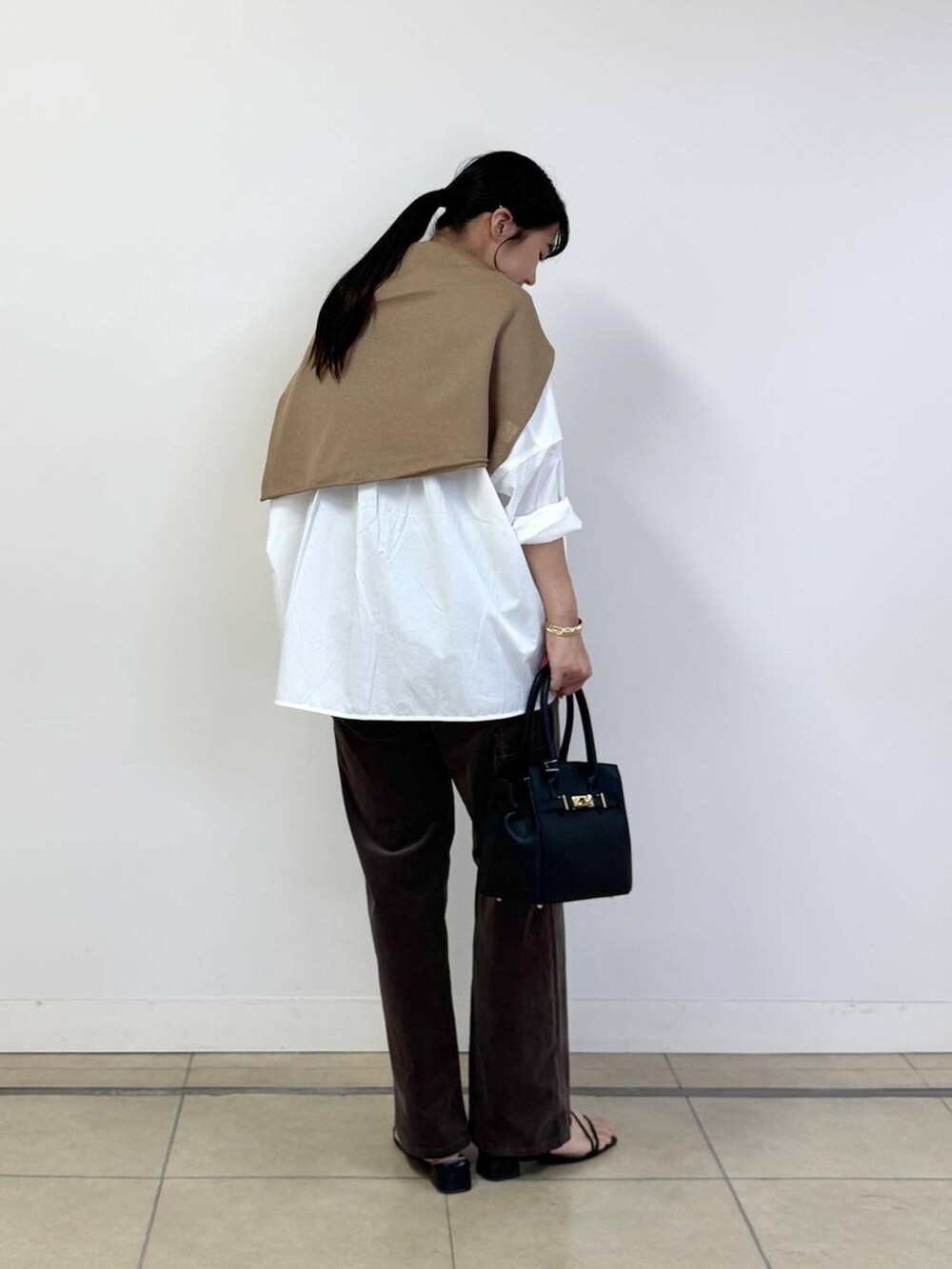 ブラック系のショルダーバッグ、ホワイト系のシャツ/ブラウス、ベージュ系のニット/セーターを着用したレディースの夏コーディネートの3枚目の写真