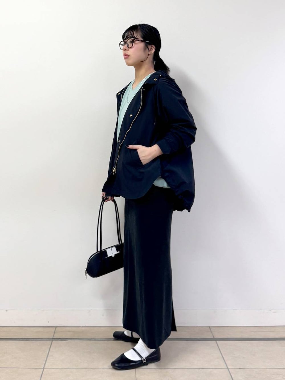 ブラック系のスカート、ブラック系のハンドバッグ、ブラック系のマウンテンパーカーを着用したレディースの春コーディネートの2枚目の写真