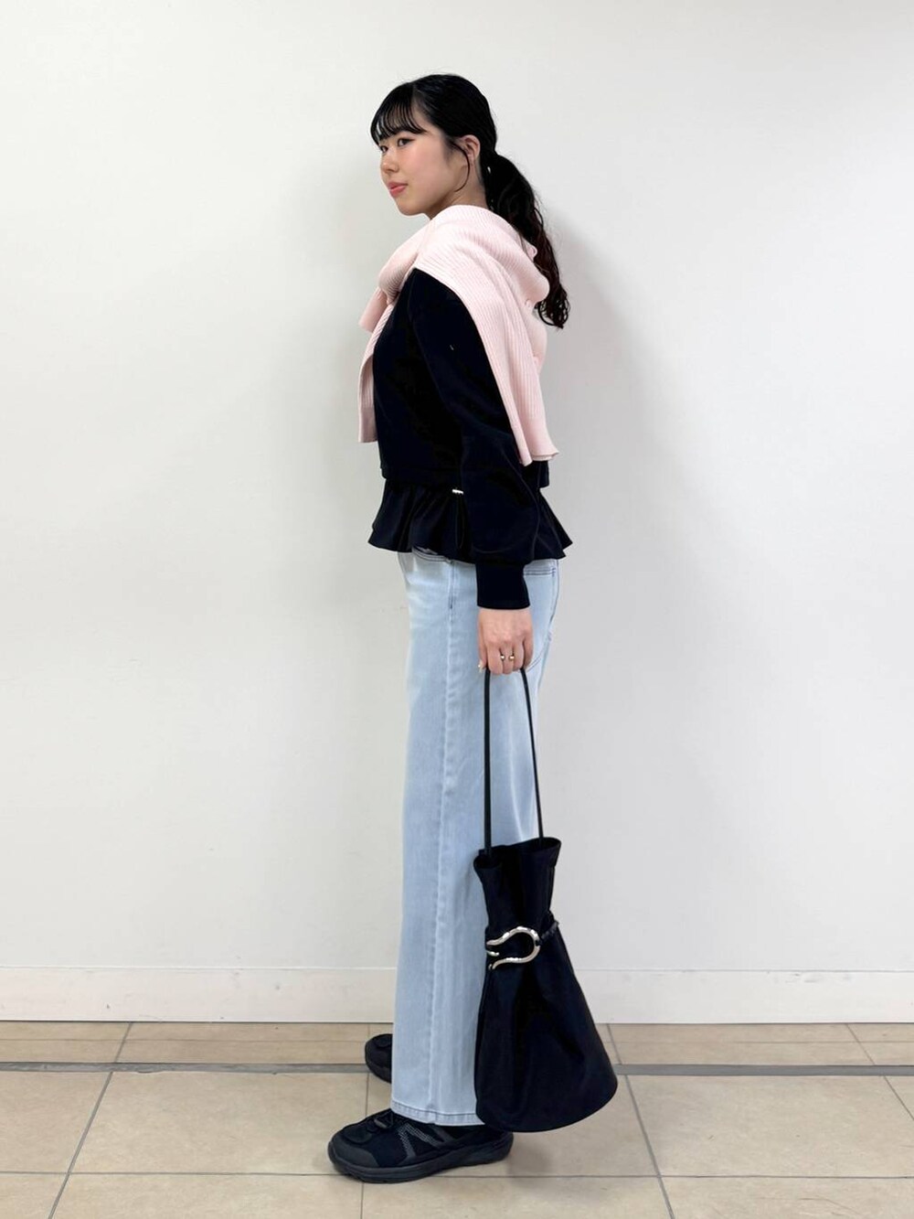 ブルー系のデニムパンツ、ピンク系のカーディガン/ボレロ、ブラック系のTシャツ/カットソーを着用したレディースの冬コーディネートの2枚目の写真