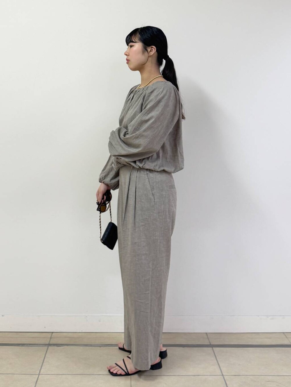 ベージュ系のシャツ/ブラウス、ベージュ系のその他パンツ、ブラック系のショルダーバッグを着用したレディースの春コーディネートの2枚目の写真