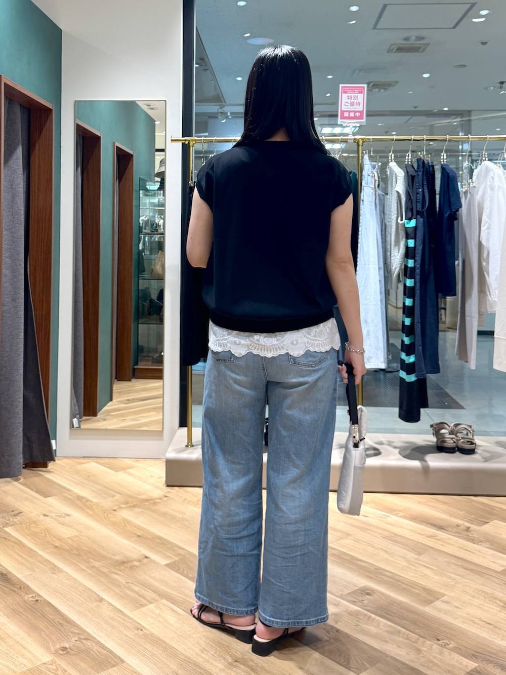 ブルー系のデニムパンツ、ホワイト系のシャツ/ブラウス、ブラック系のニット/セーターを着用したレディースの夏コーディネートの3枚目の写真